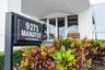Building exterior featuring multi-pane glass entry doors, expansive windows, and manicured tropical landscaping