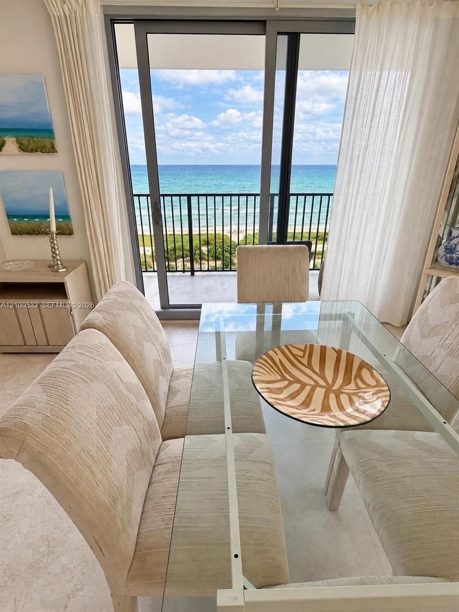 Floor-to-ceiling sliding glass door, metal balcony railing, and ocean backdrop