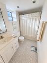 Bathroom featuring a white vanity cabinet, integrated sink with a metal faucet, mosaic tile flooring, and a tub-shower combination with recessed ceili