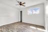 Wood-finish flooring, multi-pane window, ceiling fan with integrated lighting, and crown molding