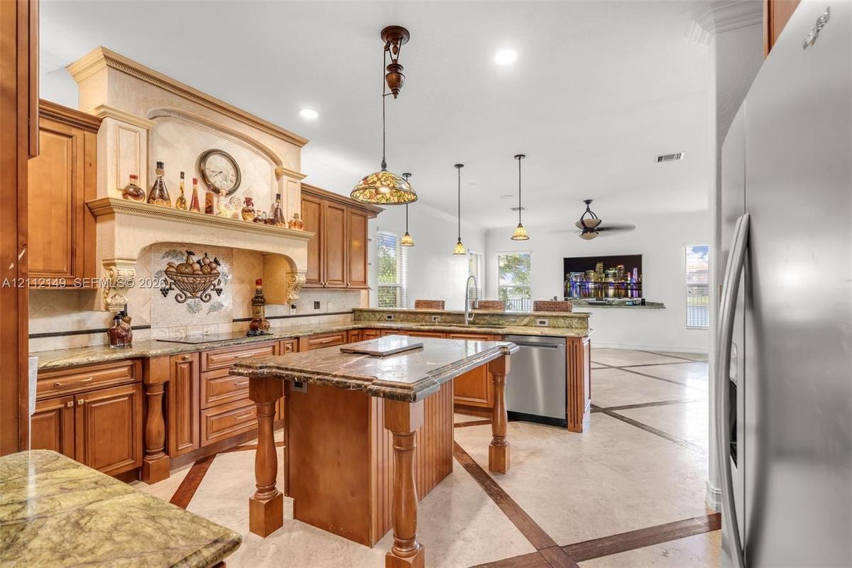 Kitchen featuring custom wood cabinetry, a central island with decorative corbels, stone countertops, a mosaic tile backsplash with a prominent range 