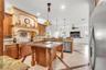 Kitchen featuring custom wood cabinetry, a central island with decorative corbels, stone countertops, a mosaic tile backsplash with a prominent range 