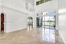 Double-height ceiling, arched architectural openings, polished stone flooring, second-level railed landing, and floor-to-ceiling glass sliding doors