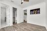 Wood-finish flooring, crown molding, ceiling fan with light kit, and walk-in closet featuring built-in shelving