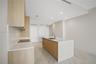 Kitchen featuring wood-finish cabinetry, an island with a stone-surface countertop, an integrated electric cooktop, and large-format tile flooring