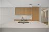 Kitchen featuring light wood-finish cabinetry, a white stone countertop island, an undermount stainless steel sink with a gooseneck faucet, and integr