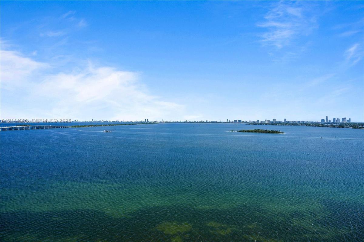 Aerial perspective of expansive open water with a distant city skyline and causeway