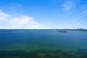 Aerial perspective of expansive open water with a distant city skyline and causeway