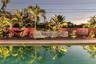 Tropical Fenced in Private Backyard with Heated Pool, uplighting, outdoor dining table, lounge chairs and plenty of seating/hammocks.