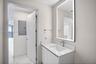 Modern floating vanity with a white countertop, integrated undermount sink, and chrome faucet, complemented by a large rectangular LED-backlit mirror