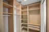 Custom storage system featuring floor-to-ceiling wooden shelving, integrated hanging rods, and two soft-close drawers