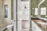 Bathroom featuring a walk-in glass-enclosed shower with metallic hardware, white cabinetry, a stone-finish countertop with an integrated basin, and te