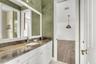 Bathroom featuring a stone-surface vanity with an integrated oval sink, white cabinetry, a full-width mirror, and textured wall treatment