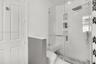 Walk-in shower featuring a glass enclosure, square rainfall shower head, handheld sprayer, built-in bench, and recessed wall niches