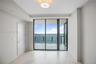 Floor-to-ceiling sliding glass doors, private balcony with metal railing, neutral tile flooring, and flush-mount drum ceiling light