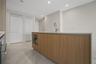 Kitchen island featuring wood-finish cabinetry, a white stone countertop, a stainless steel undermount sink, a high-arc faucet, and integrated built-i