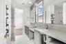 Dual-vanity bathroom featuring speckled stone-finish countertops, undermount sinks, geometric-patterned wall tile accents, and recessed wall shelving