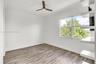 Wood-finish flooring, white built-in shelving, double-pane window, and modern ceiling fan with integrated lighting