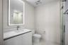 Modern vanity featuring a stone countertop, integrated sink, and wall-mounted, back-lit mirror