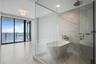 Freestanding soaking tub, glass-enclosed walk-in shower with rain showerhead, floor-to-ceiling stone-look tiling, and floor-to-ceiling windows with ba
