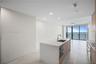 Kitchen island with stone-surface countertop, under-mount stainless steel sink, wood-finish cabinetry, floor-to-ceiling glass doors, and light-tone ti