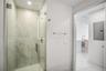 Walk-in shower featuring large-format stone-patterned tile, frameless glass enclosure, and recessed lighting