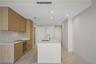 Kitchen featuring wood-finish cabinetry, stone-surface countertops, center island with undermount sink, built-in stainless steel oven, and stone-finis