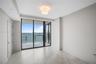 Floor-to-ceiling sliding glass doors, private balcony, large-format tile flooring, and overhead flush-mount lighting
