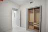 Built-in closet featuring dual hanging rods, fixed shelving, and integrated drawer storage, complemented by stone-finish flooring and solid core swing