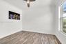 Room featuring wood-finish flooring, crown molding, and a ceiling fan with integrated lighting