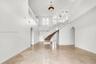 Grand foyer featuring high ceilings, curved staircase with white railings, polished stone flooring, arched entryways, and recessed lighting