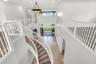 Grand foyer featuring a curved staircase, stone tile flooring, multi-level ceiling heights, white wood railings, and a tiered chandelier