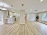 Open-concept interior featuring wood-finish flooring, a kitchen peninsula with integrated seating, built-in wine storage, recessed lighting, and a mod