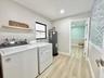Laundry room featuring wood-finish flooring, recessed lighting, and textured accent wall covering