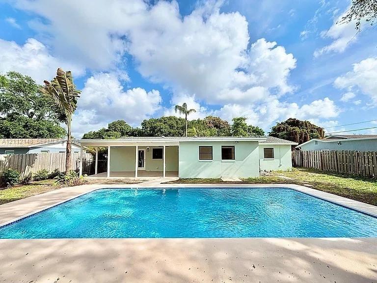 In-ground rectangular swimming pool featuring a concrete deck and a covered patio area with vertical support pillars
