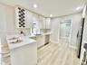Kitchen featuring white Shaker-style cabinetry with integrated wine rack, solid-surface countertops, stainless steel appliances, and wood-finish floor