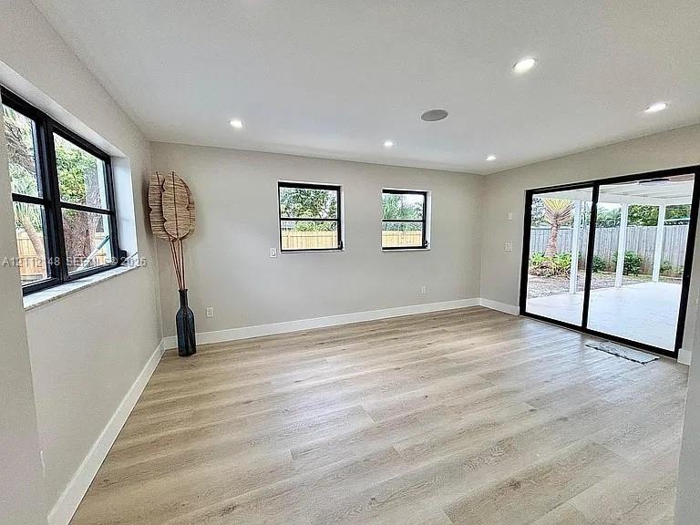 Interior space featuring wood-finish flooring, recessed lighting, black-framed windows, and sliding glass doors with direct patio access