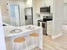 Kitchen featuring white cabinetry, solid-surface countertops, stainless steel appliances, and wood-finish flooring