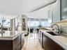 Modern kitchen featuring quartz countertops, dark wood-finish cabinetry, floor-to-ceiling windows, stacked-stone backsplash, and polished stone floori