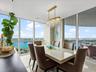 Floor-to-ceiling windows, crystal chandelier, and light-toned flooring featuring a expansive balcony and panoramic water exposure