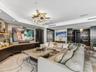 Custom built-in cabinetry with integrated shelving, stone-surfaced center table, polished stone flooring, and multi-tiered contemporary statement ligh