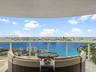 Covered private balcony featuring stone flooring and a glass railing with panoramic water and skyline scenery