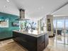 Kitchen featuring a center island with a stone countertop, dark cabinetry, a stainless steel chimney-style range hood, recessed ceiling lighting, and 
