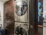 Stacked stainless steel laundry appliances paired with floor-to-ceiling dark wood-finish cabinetry
