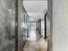 Hallway featuring polished stone flooring, custom Venetian plaster wall finishes, recessed ceiling lighting, and dark-finished door casing