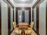 Dark-finish built-in cabinetry featuring frosted glass panels with gold-tone trim, crown molding, and stone flooring