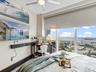 Floor-to-ceiling windows with urban skyline backdrop, custom wall-mounted shelving, overhead ceiling fan, and roller shades