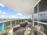 Covered wrap-around balcony featuring stone flooring, floor-to-ceiling glass paneling, and metal railing