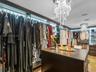 Custom walk-in closet featuring extensive dark-finish built-in shelving, integrated cabinet lighting, a central storage island, and two tiered crystal