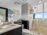 Bathroom featuring a stone-surface vanity with an integrated undermount sink, dark-finish cabinetry, floor-to-ceiling tile shower enclosure, glass par